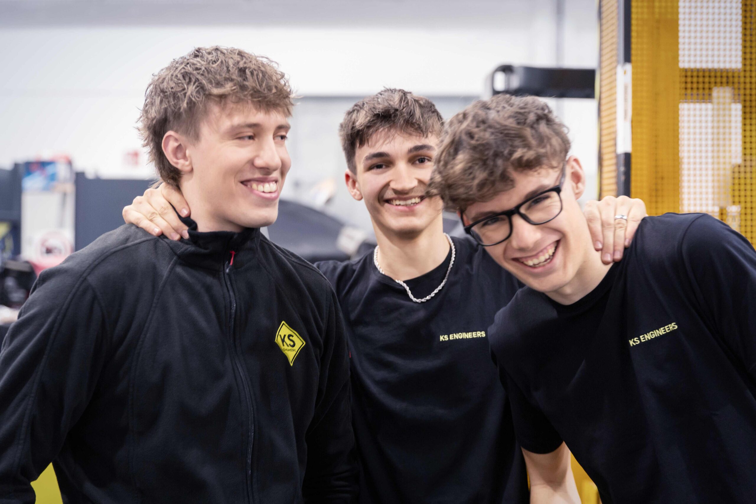 drei junge Personen stehen zusammen und lachen